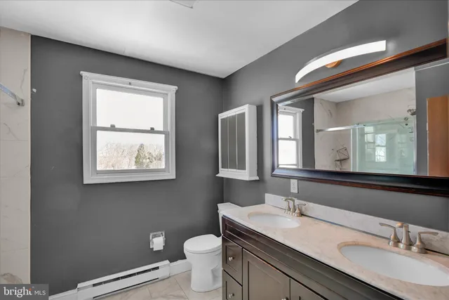 a bathroom with a granite countertop sink toilet a large mirror and a window