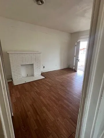 a view of an empty room and wooden floor and a window