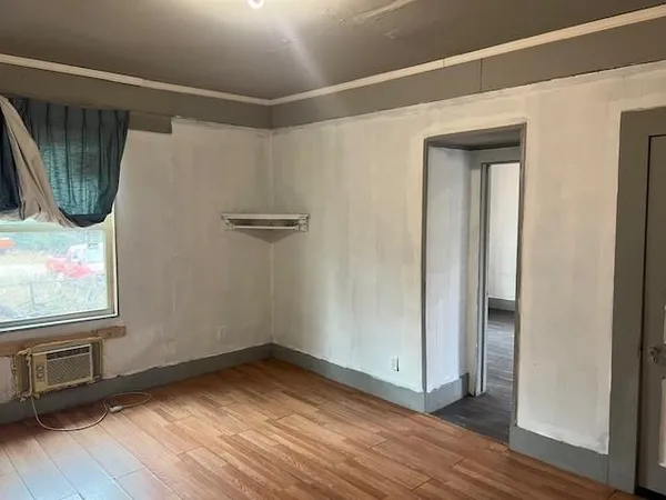 a view of an empty room with wooden floor and a window