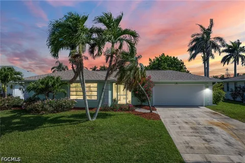 front view of house with a yard and palm trees