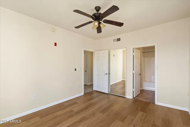an empty room with wooden floor fan and windows