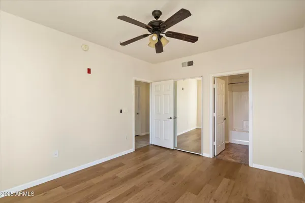 an empty room with wooden floor fan and windows