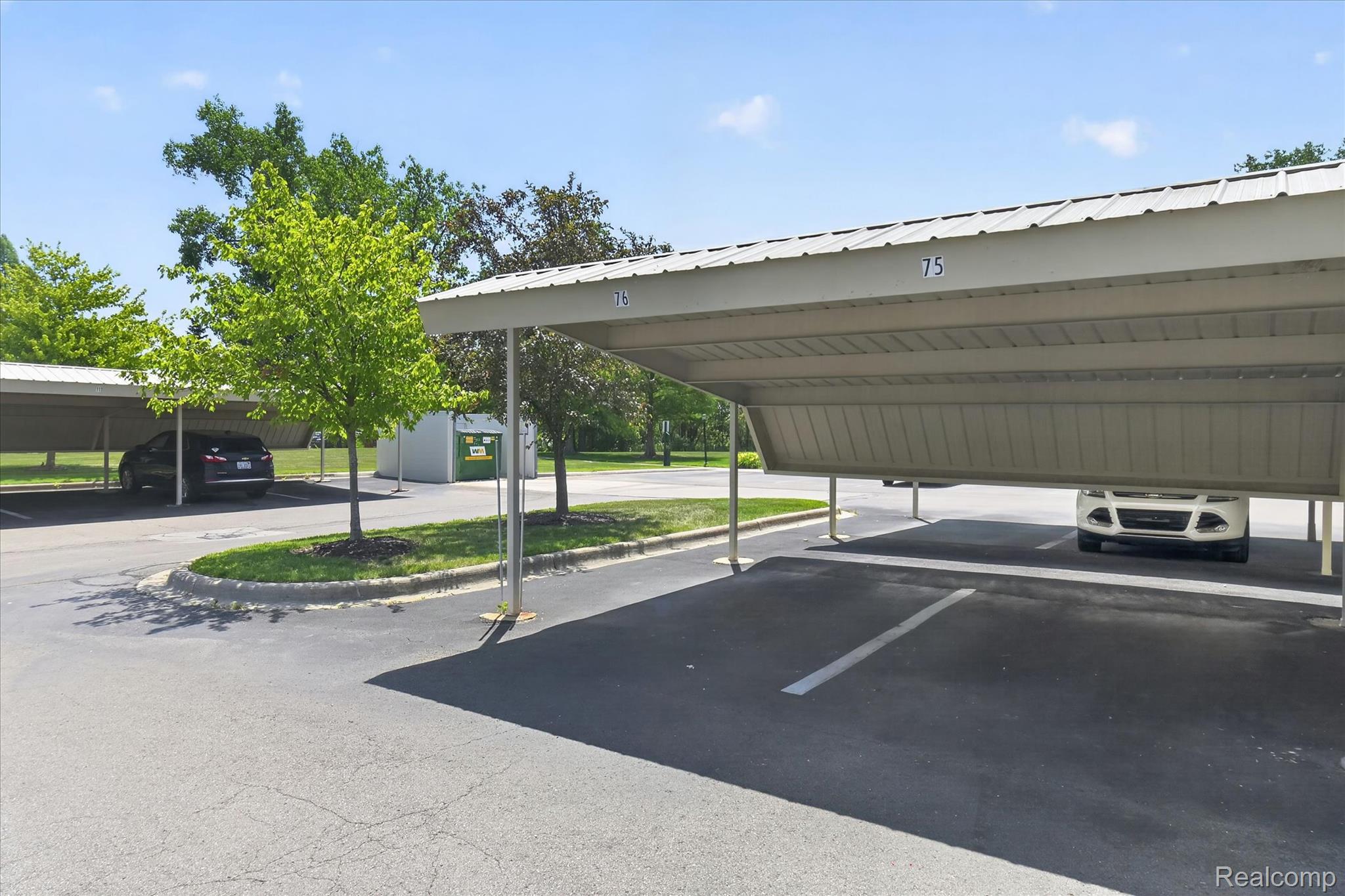 45720 Prairiegrass Court Belleville, MI 48111 - Photo 31 of 31 Covered parking structure featuring multiple bays, a corrugated metal roof, and numbered spaces