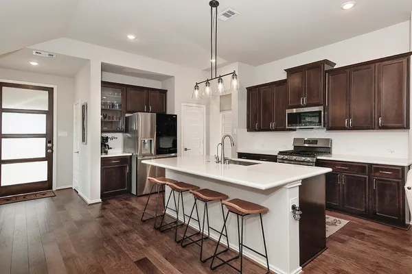 a kitchen with stainless steel appliances granite countertop a stove top oven a refrigerator a sink and dishwasher with wooden floor