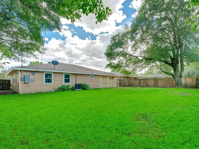 a view of a yard in front of a house with large trees