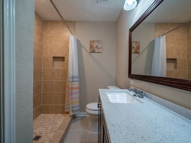 a bathroom with a granite countertop sink a mirror and a shower