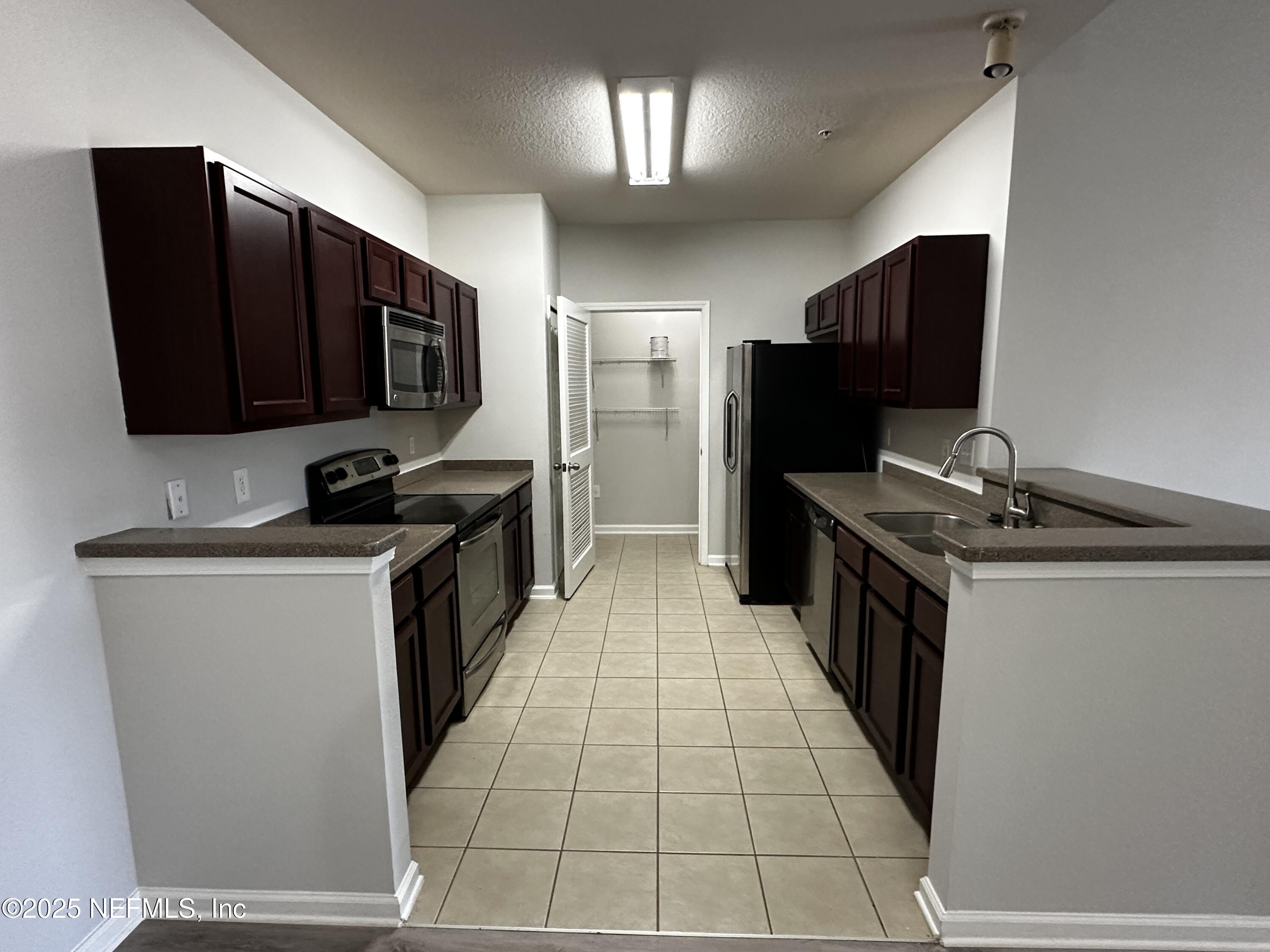 4917 Key Lime Drive, Unit 306 Jacksonville, FL 32256 - Photo 14 of 51 a kitchen with stainless steel appliances a refrigerator and a stove top oven