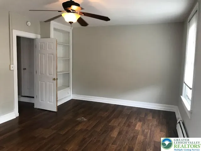 a view of empty room with wooden floor and fan