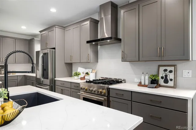 a kitchen with stainless steel appliances kitchen island granite countertop a refrigerator a sink dishwasher a stove and white countertops with cabinets