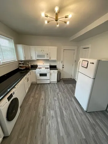 a kitchen with kitchen island wooden floors appliances and cabinets