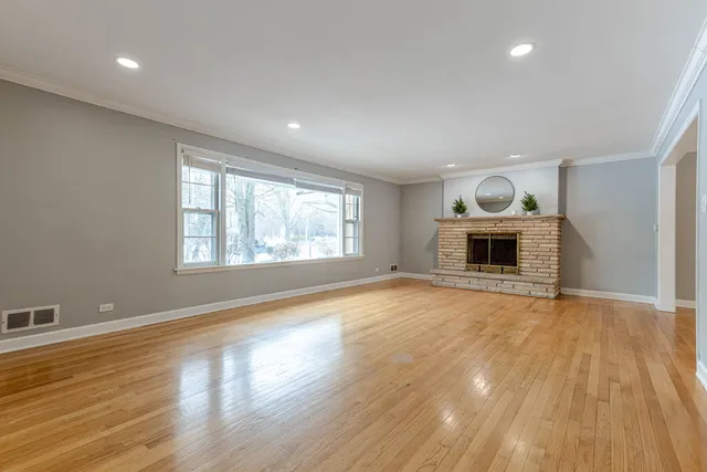 an empty room with wooden floor fireplace and windows