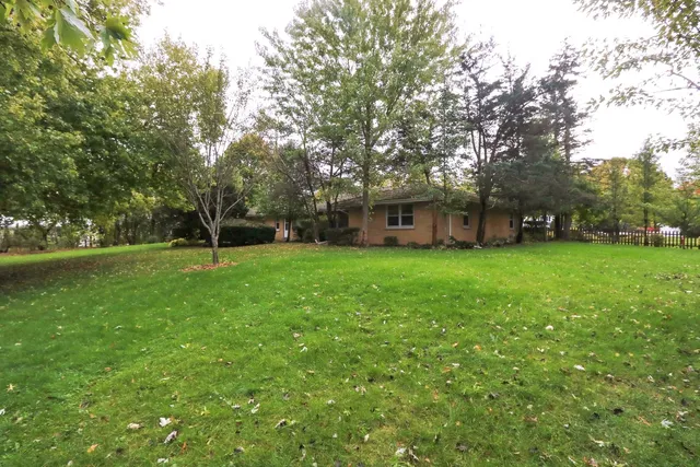 a view of a house with a big yard and large trees
