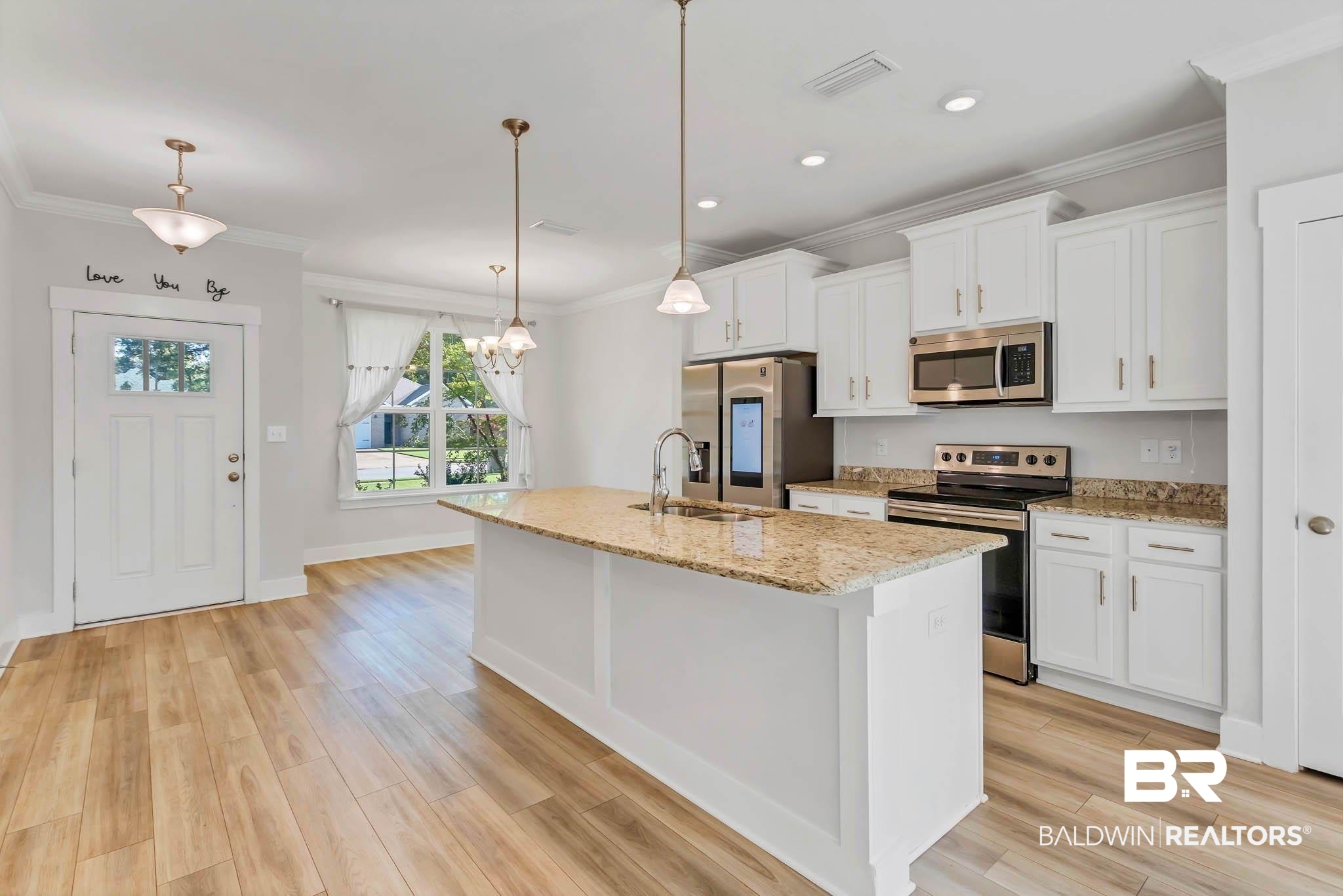16461 Prado Loop Loxley, AL 36551 - Photo 12 of 78 Kitchen featuring stainless steel appliances, crown molding, a center island with sink, light stone counters, and white cabinets