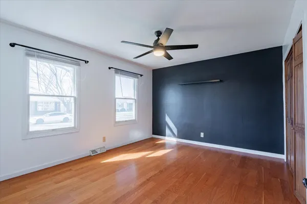 a view of empty room with wooden floor and fan