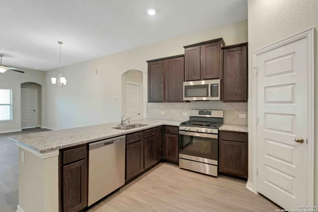 a kitchen with stainless steel appliances granite countertop a stove a sink and a microwave