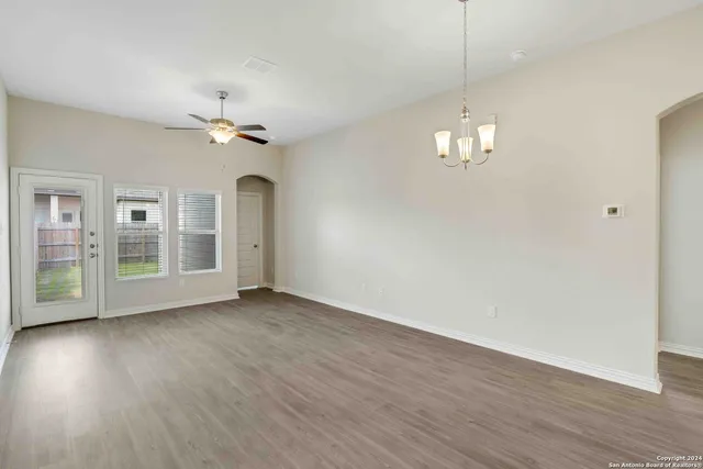 a view of an empty room with a window and wooden floor