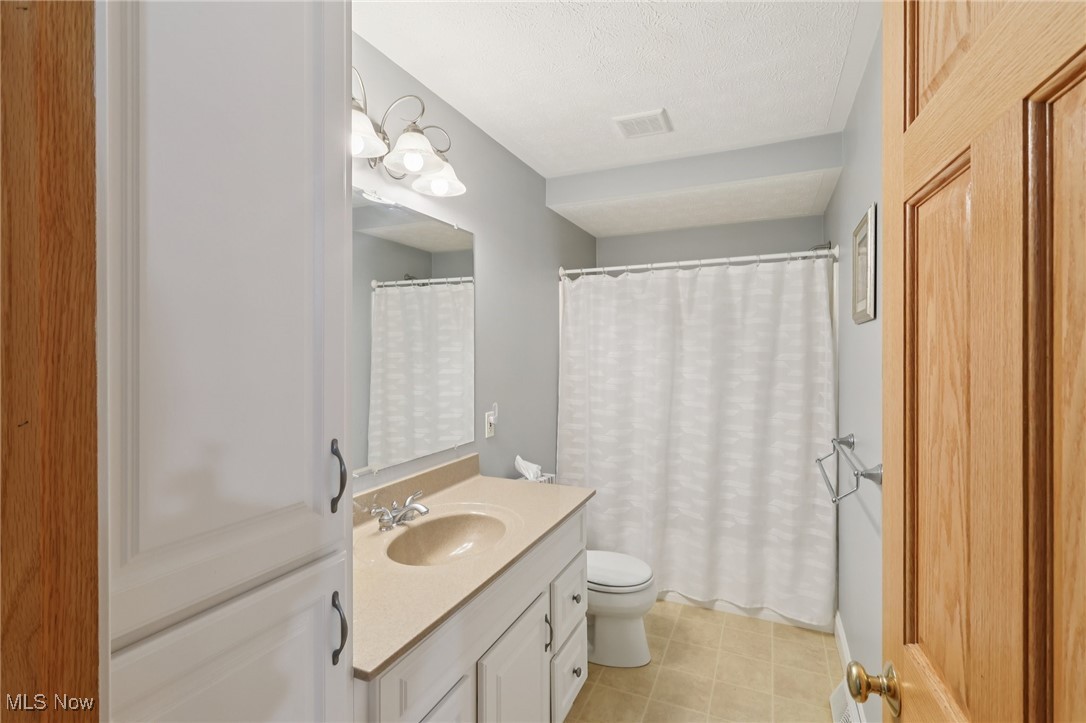5877 Pearl Road Cleveland, OH 44130 - Photo 17 of 42 Full bathroom featuring vanity, a textured ceiling, light tile patterned floors, and a shower with shower curtain
