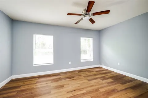 a view of a big room with wooden floor and windows