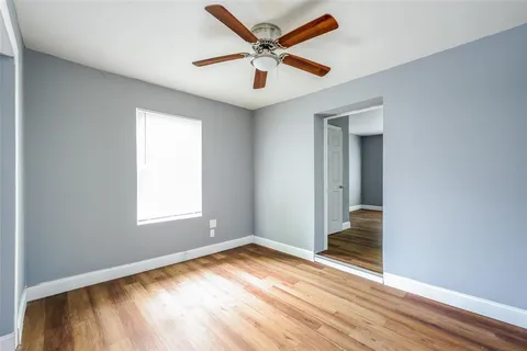 a view of empty room with wooden floor and fan