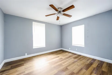 a view of a big room with wooden floor and windows