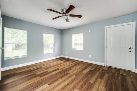 a view of an empty room with a window and wooden floor