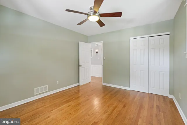 an empty room with wooden floor a ceiling fan and closet