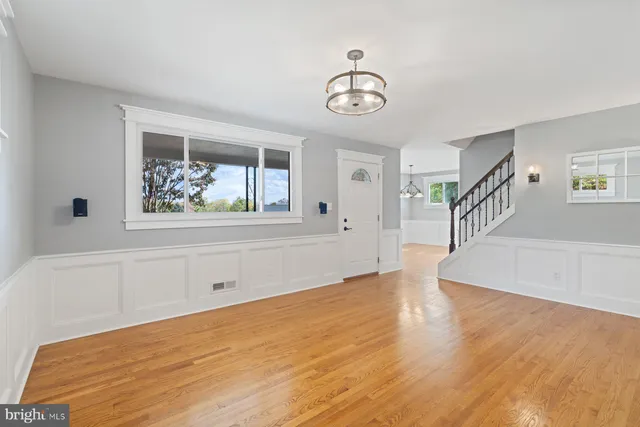a view of an empty room with wooden floor and windows