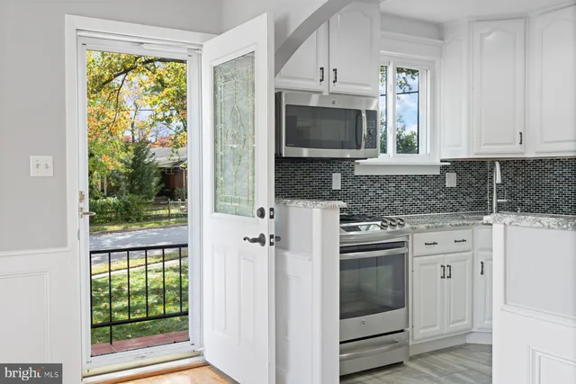 a kitchen with white cabinets appliances and a window