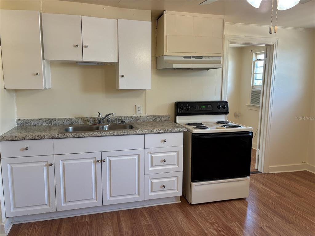 507 Cleveland Avenue Southwest, Unit 2 Largo, FL 33770 - Photo 7 of 20 a kitchen with granite countertop white cabinets and a stove with wooden floor