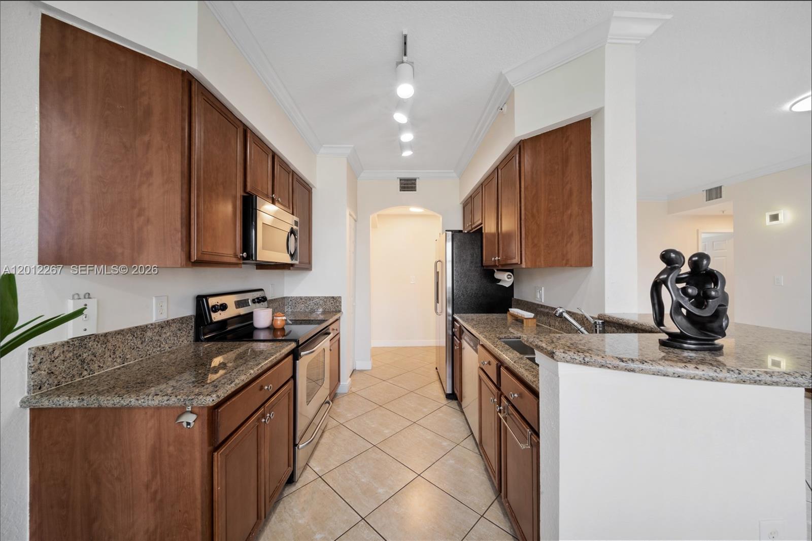 9021 Southwest 94th Street, Unit 310 Miami, FL 33176 - Photo 16 of 41 a kitchen with granite countertop a sink a stove and a wooden cabinets