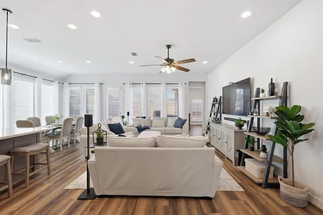 a living room with furniture a large window and wooden floor