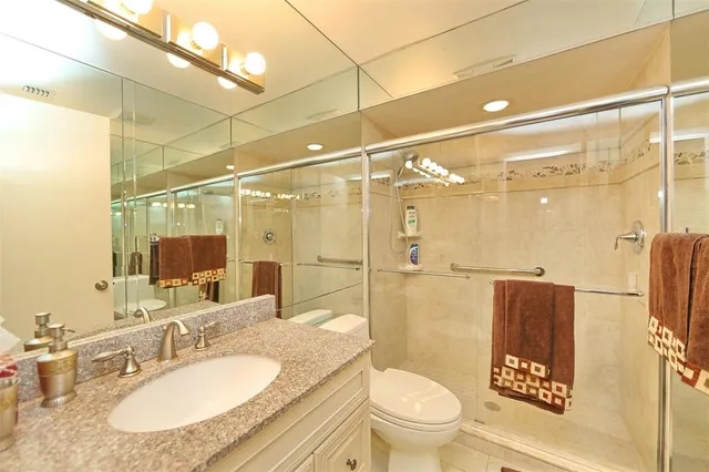 a bathroom with a granite countertop sink toilet a mirror and shower