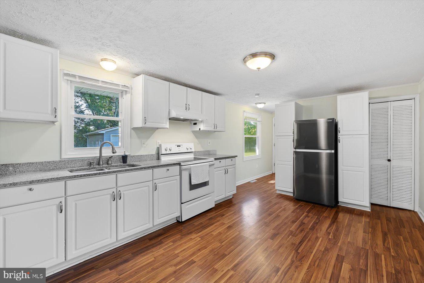 11193 Henry Griffin Road King George, VA 22485 - Photo 17 of 35 a kitchen with stainless steel appliances granite countertop a refrigerator a sink dishwasher a stove with wooden floors and cabinets