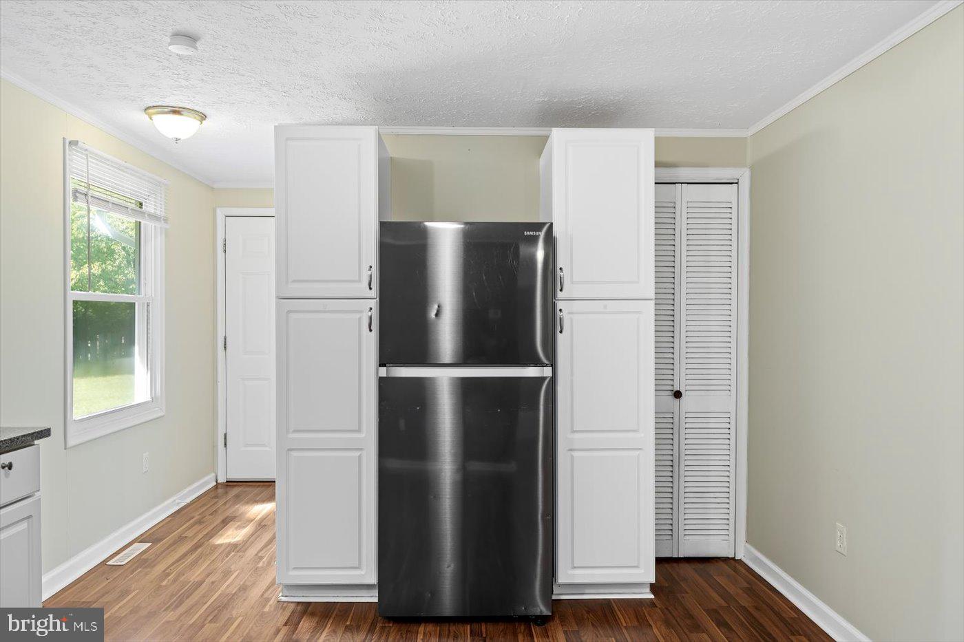 11193 Henry Griffin Road King George, VA 22485 - Photo 18 of 35 a view of a refrigerator in kitchen and an empty room with wooden floor