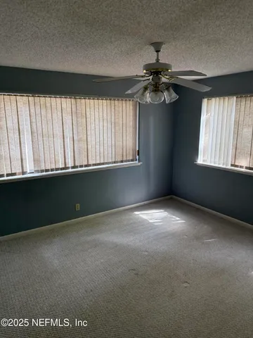 an empty room with windows and fan