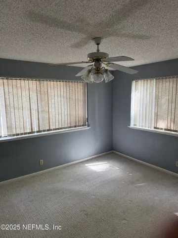 an empty room with windows and fan
