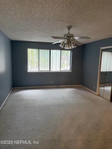 an empty room with windows and chandelier fan