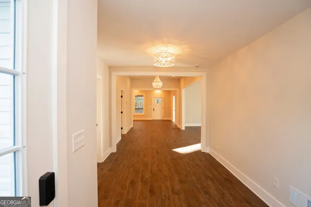 a view of an empty room with window and wooden floor