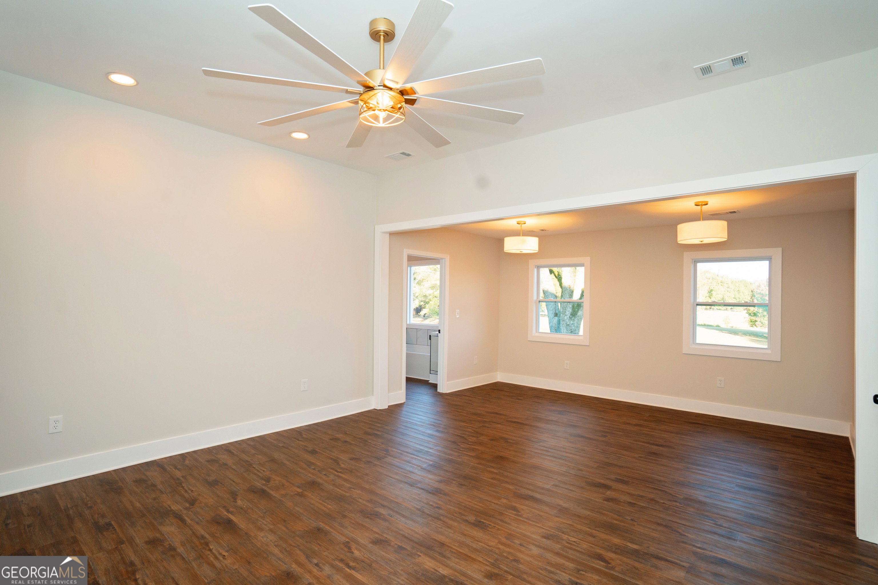 269 Martin Dairy Road Milner, GA 30257 - Photo 26 of 71 an empty room with wooden floor chandelier fan and windows