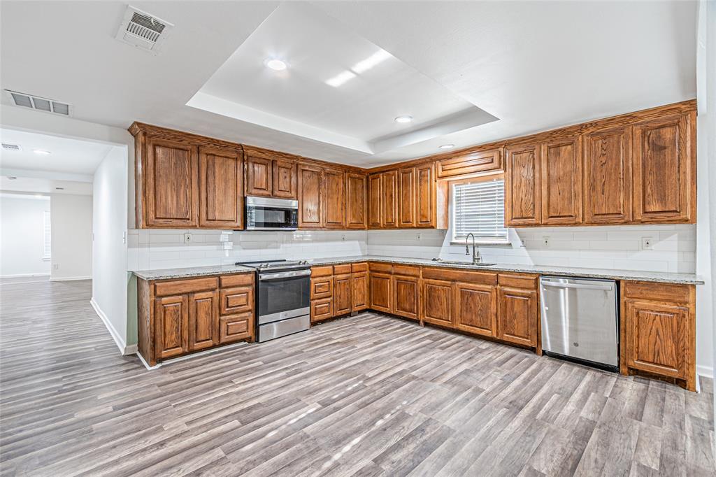 605 Lloyd Italy, TX 76651 - Photo 17 of 30 a kitchen with granite countertop wooden floors wooden cabinets and stainless steel appliances
