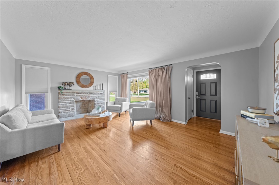 6315 Brookside Road Independence, OH 44131 - Photo 2 of 41 Living area with a fireplace, arched walkways, baseboards, and light wood-type flooring