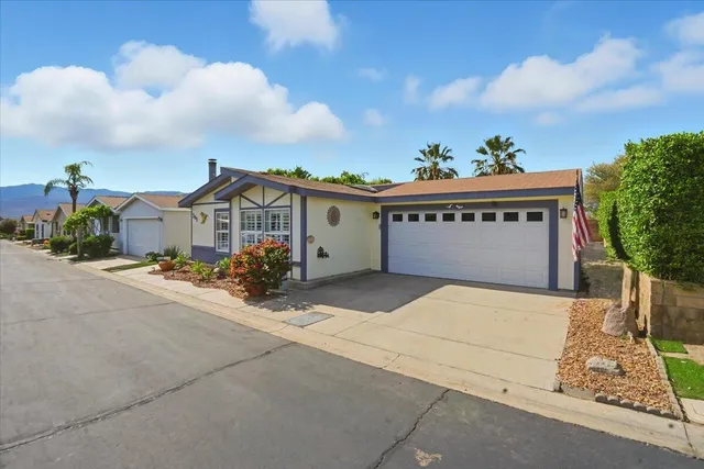 a view of a white house with a yard and potted plants