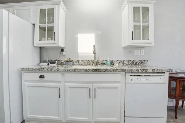 a sink with granite countertop cabinets and window