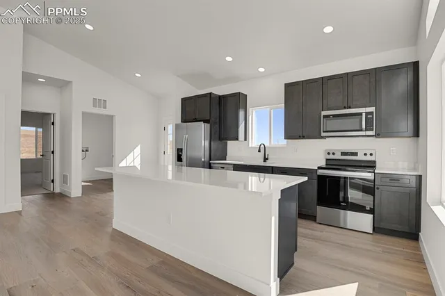 a large kitchen with stainless steel appliances kitchen island granite countertop a stove a sink a refrigerator and a microwave