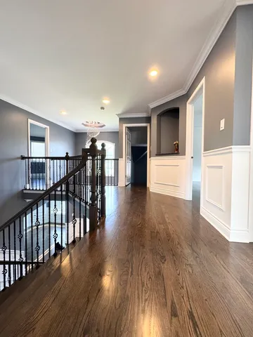 a view of a hallway with wooden floor and seating space