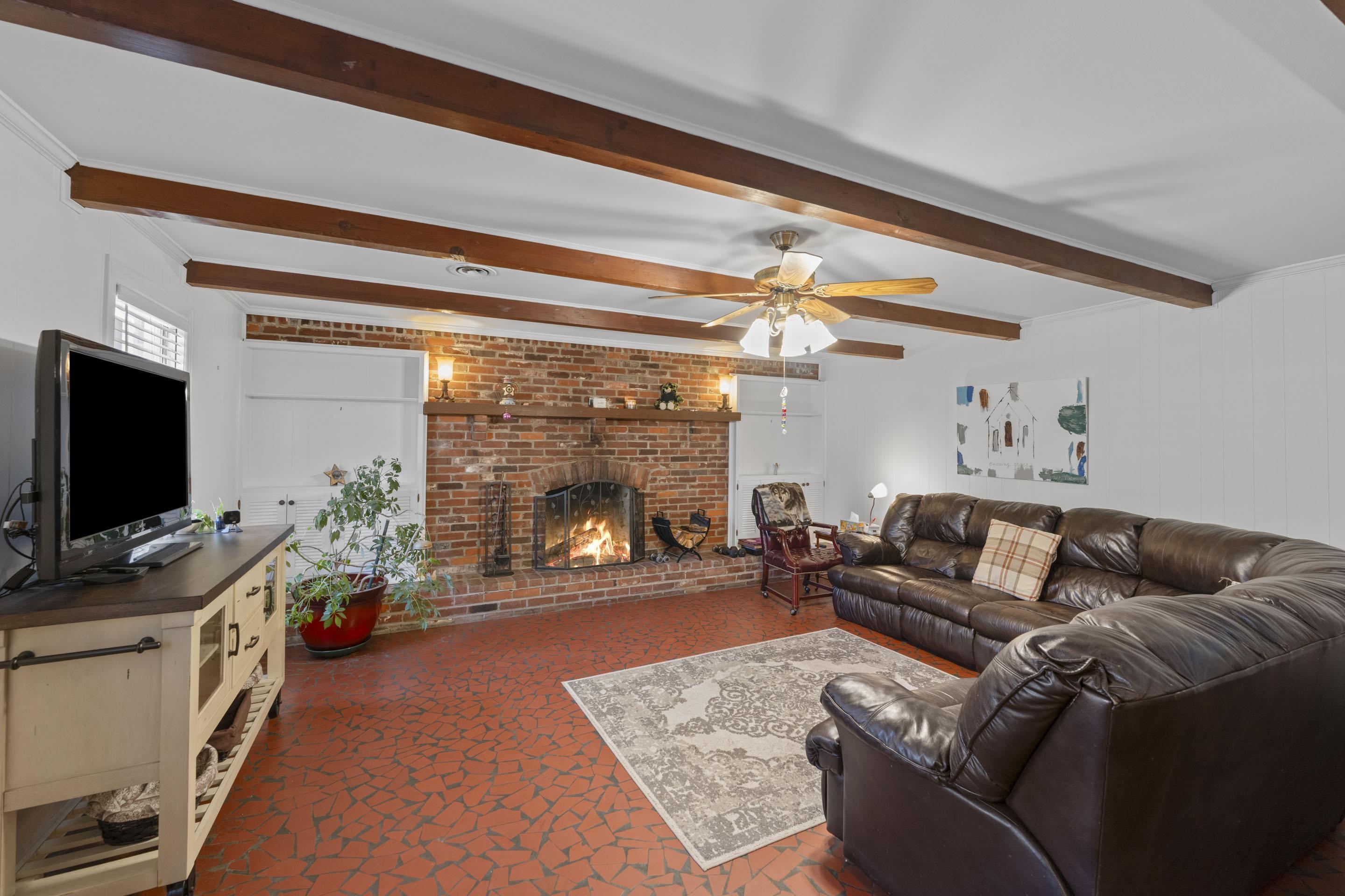 1694 South White Station Road Memphis, TN 38117 - Photo 10 of 26 The den is the heart of the home — complete with charming wood beams, a wood-burning fireplace, and broken terracotta tile floors that add character.