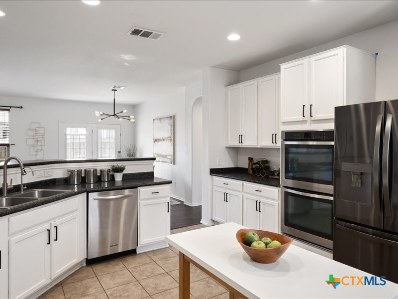 18817 Star Gazer Way Pflugerville, TX 78660 - Photo 5 of 36 a kitchen with stainless steel appliances a sink a stove a refrigerator a counter space and cabinets