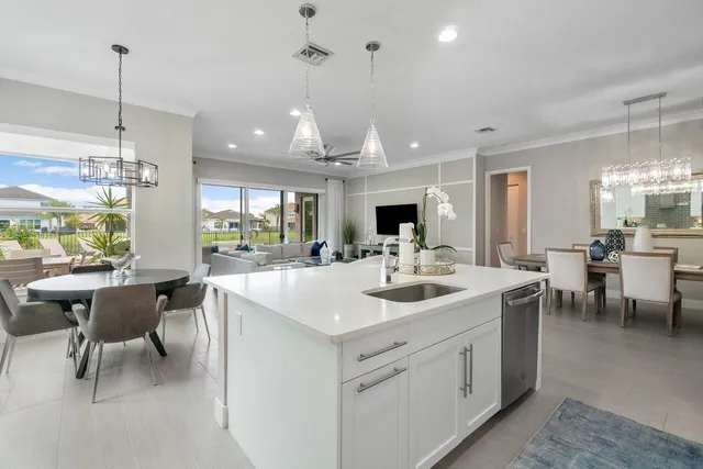 a open kitchen with stainless steel appliances kitchen island a white table chairs and a sink