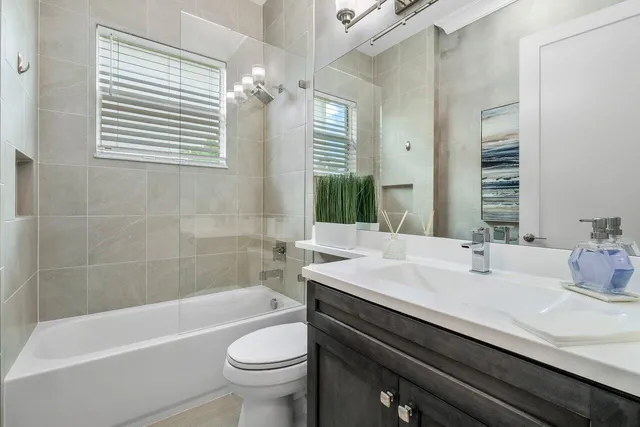 a bathroom with a sink a toilet a mirror a bathtub and shower