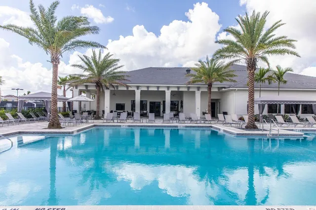 a view of an house with swimming pool and chairs